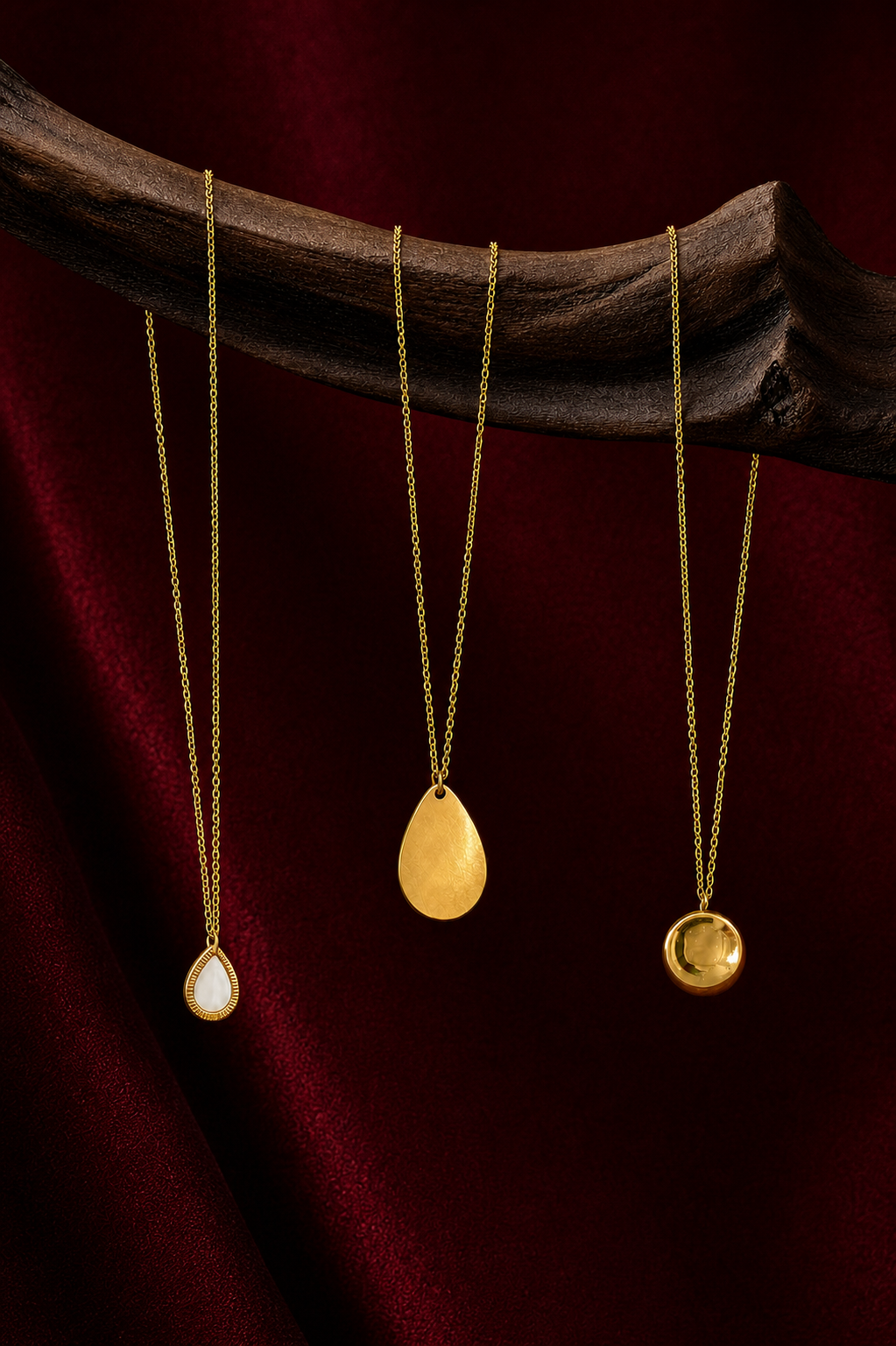 Collection de colliers dorés Amani sur fond rouge grenat