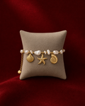 Bracelet marin avec perles et breloques dorées sur fond rouge signature Amani by Layal