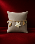 Bracelet océan à fleur nacrée et coquillages sur fond rouge signature Amani by Layal