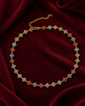 Collier doré à fleurs multicolores sur fond rouge signature Amani by Layal